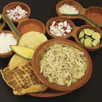Pozole con sus guarniciones: cebolla, rábano, limón, aguacate y tostada